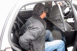 A suspect in handcuffs sitting in the back of a police car after being arrested. Miranda rights only apply when a suspect is both in custody and being interrogated.