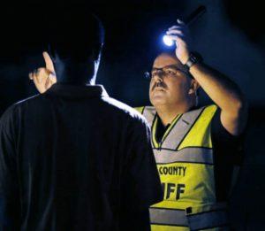 A police officer administering a Horizontal Gaze Nystagmus (HGN) Test to a driver at a DUI checkpoint